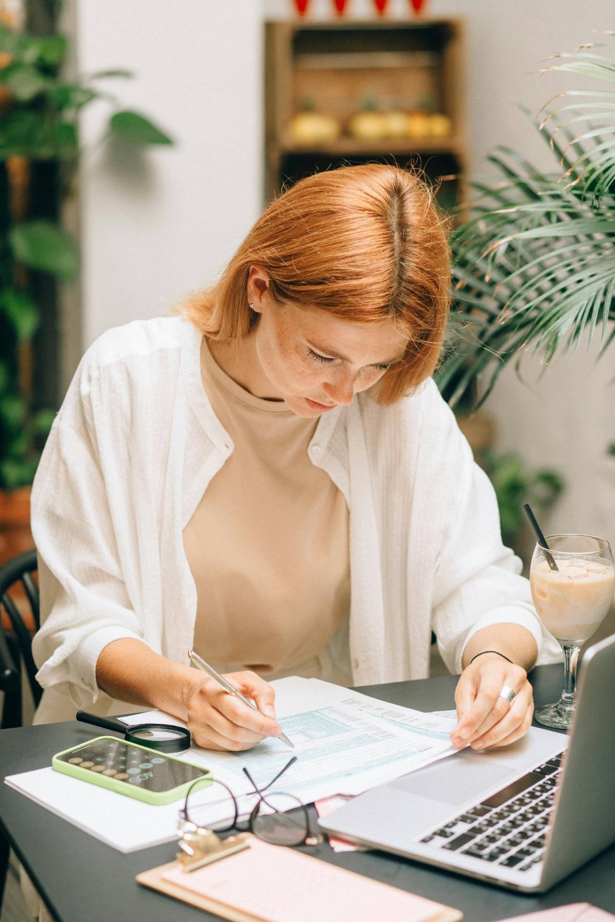 a woman working with papers and a laptop